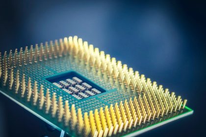 Close-up de um chip de computador com contatos dourados sobre fundo azul.