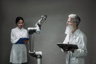 Dois cientistas trabalham com um braço robótico em um laboratório de pesquisa e inovação tecnológica.