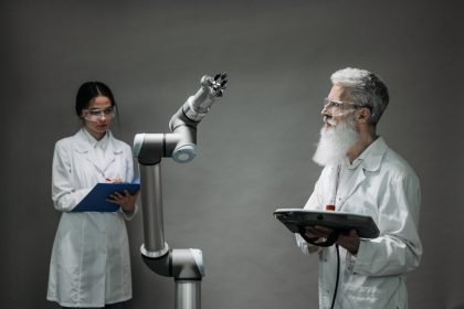 Dois cientistas trabalham com um braço robótico em um laboratório de pesquisa e inovação tecnológica.