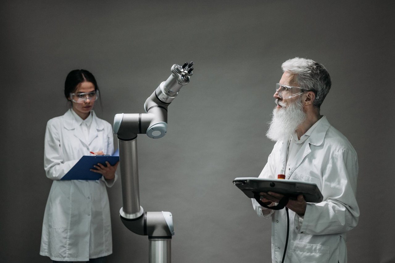 Dois cientistas trabalham com um braço robótico em um laboratório de pesquisa e inovação tecnológica.